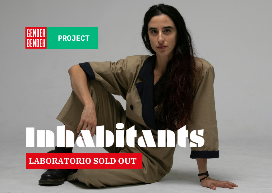 Luna Cenere è seduta a terra in posa rilassata, ha lunghi capelli scuri, indossa una tuta beige con dettagli blu scuro e anfibi neri. Sullo sfondo grigio chiaro, in alto a sinistra compare il logo di Gender Bender e la scritta 'PROJECT' su sfondo verde.